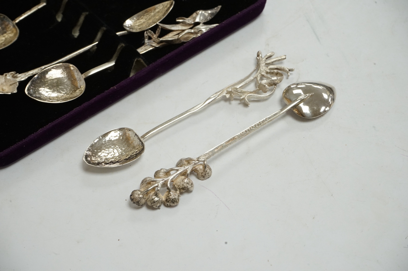 A cased set of six 20th century Australian sterling 925 coffee spoons, by Harris & Sons, with hammered bowls and terminals models and different flowers including Golden Wattle and Boronia, 11.7cm. Condition - fair to goo